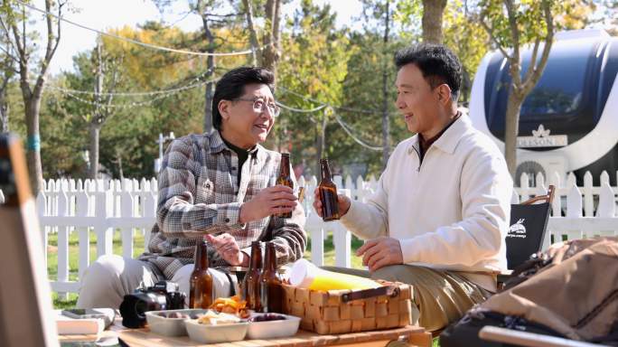 两个老年男人坐在房车露营院子里聊天喝啤酒