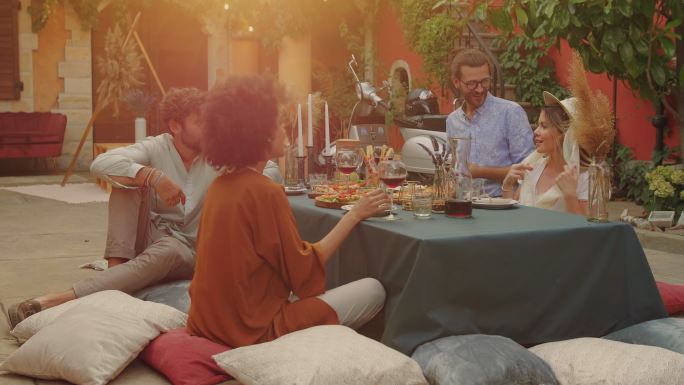 日落时分，一群朋友在托斯卡纳的度假屋里欢声笑语，围坐在桌子旁