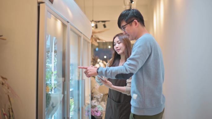 亚洲中国女花艺师向顾客解释从冰箱中选择的不同花卉包装