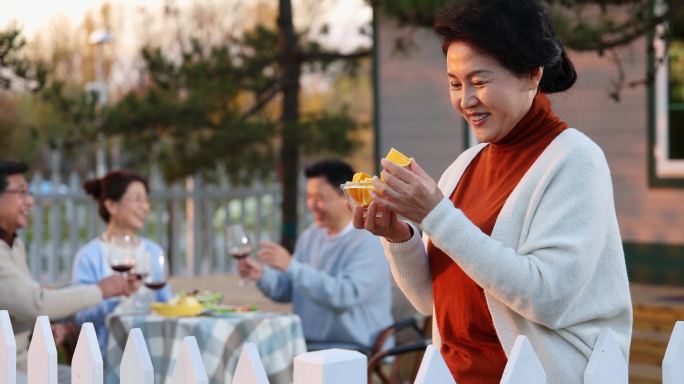 夕阳下中老年朋友在庭院里聚会喝酒聊天