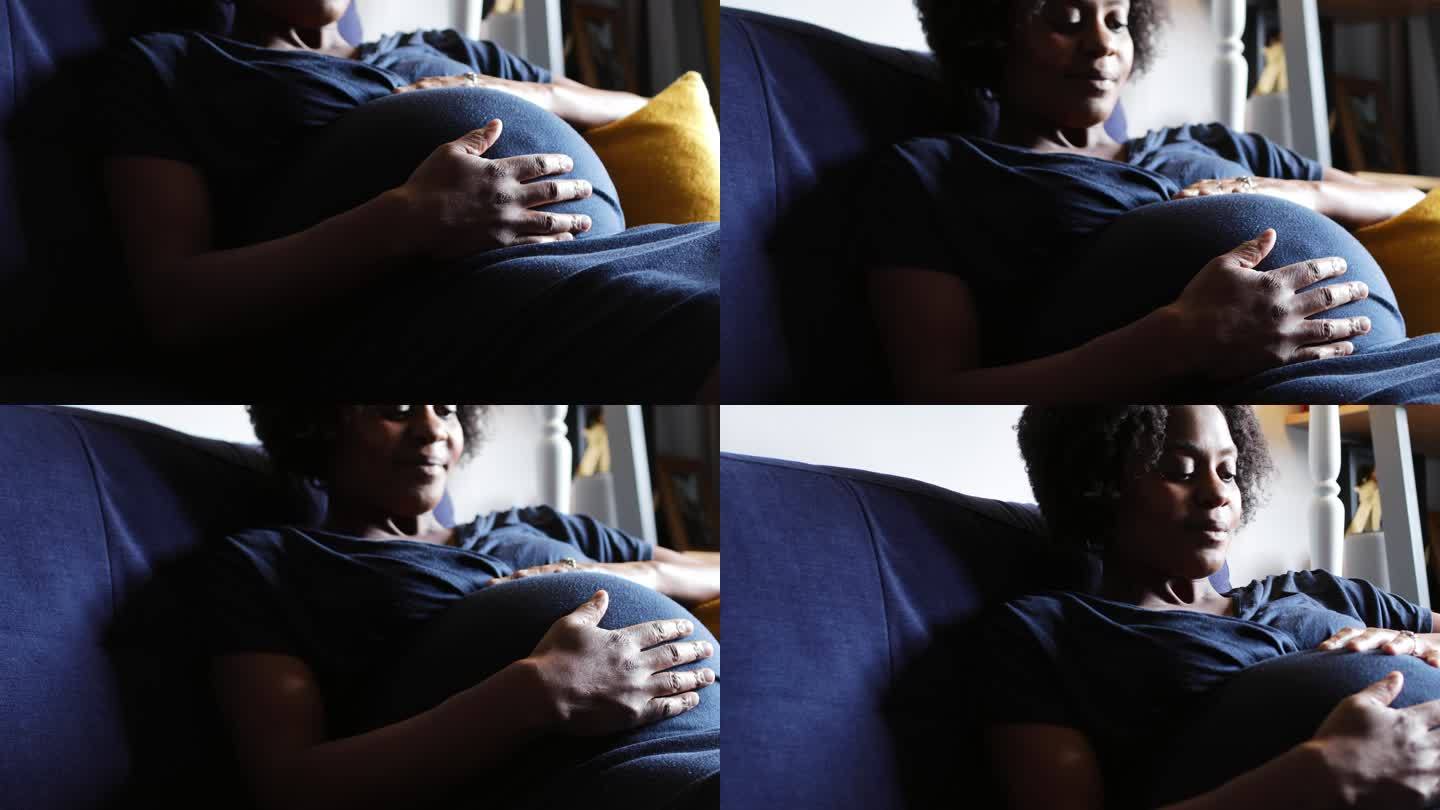 安静的孕妇在沙发上抚摸腹部放松