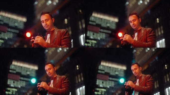 一名男子晚上在城市里看着相机里的照片