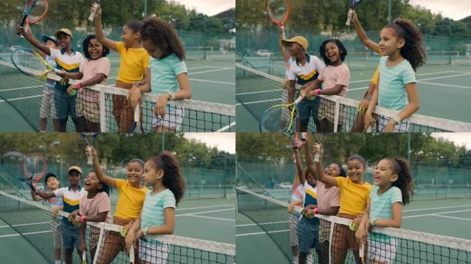 一群孩子在打网球。快乐、可爱、多样化的网球运动员站在一起，拿着球拍，在球场上微笑