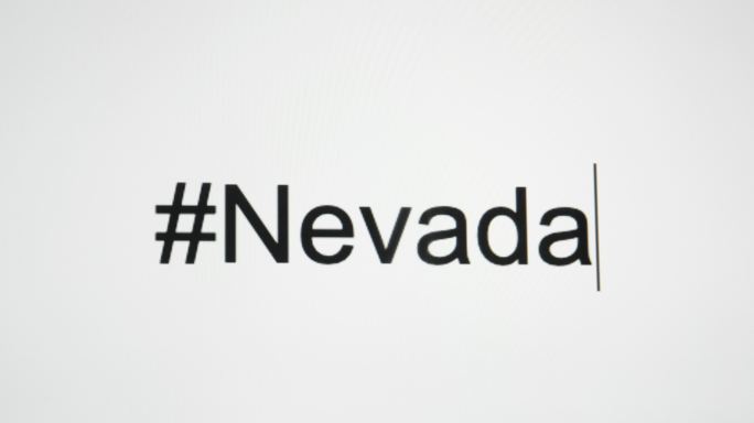 一个人在电脑屏幕上键入“#Nevada”，然后跟随州缩写