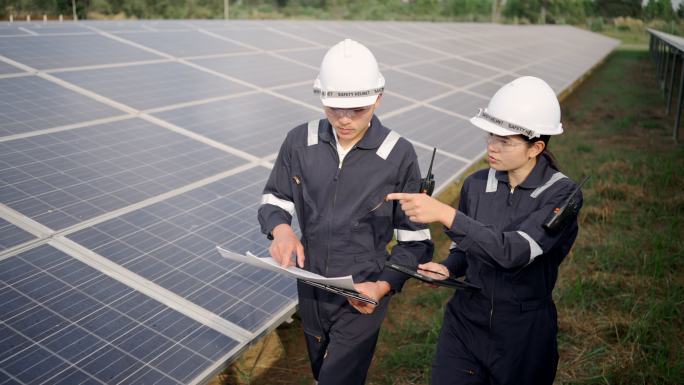太阳能电池板发电站，电气工程师检查建筑外的太阳能电池场。