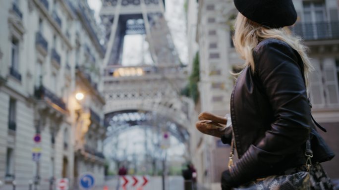 SLO MO时尚的法国女人沿着埃菲尔铁塔带着法棍走在街上