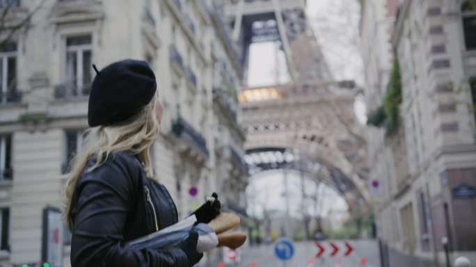 SLO MO时尚的法国女人在埃菲尔铁塔边的街上吃法棍面包