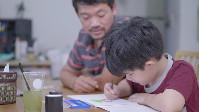 亚洲男孩和父亲在家里画水彩