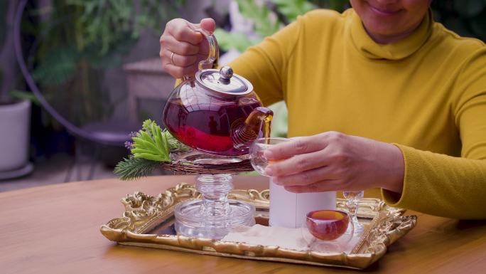 女人将茶从玻璃壶倒入杯中，茶道概念