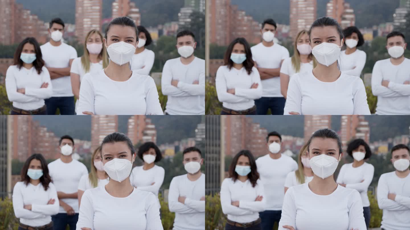 在新冠肺炎大流行期间，一名拉丁美洲妇女带领一群志愿者，所有人都戴着防护口罩和面对镜头