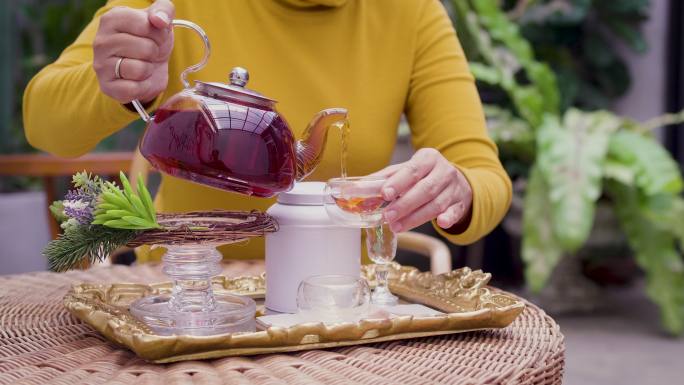 女人将茶从玻璃壶倒入杯中，茶道概念
