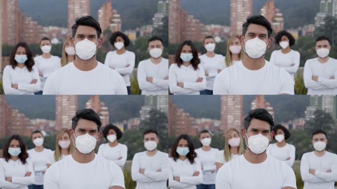 在新冠肺炎大流行期间，一名拉丁美洲男子带领一群志愿者，所有人都戴着防护口罩和面对镜头