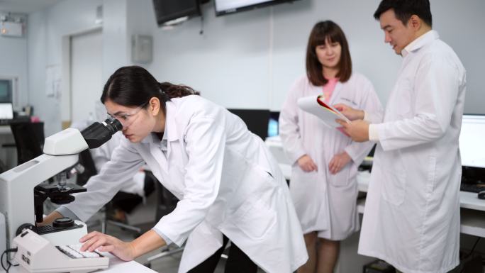 专家医生在实验室讨论治疗事项和显微镜检查在实验室。