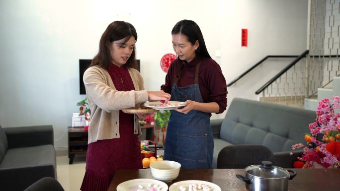 两名亚洲中国妇女在中国新年团圆饭上做汤圆