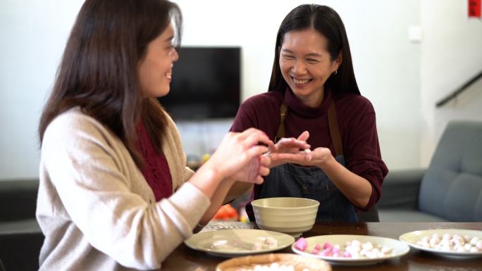 两名亚洲中国妇女在中国新年团圆饭上做汤圆