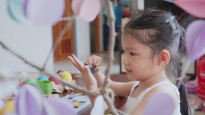 可爱的亚洲女孩正开心地给她的手上色。孩子们玩得很开心，为复活节做准备，画鸡蛋和装饰鸡蛋。