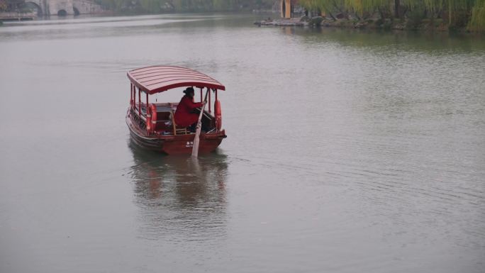 扬州瘦西湖阴雨天在雨中行驶中摇橹船船娘