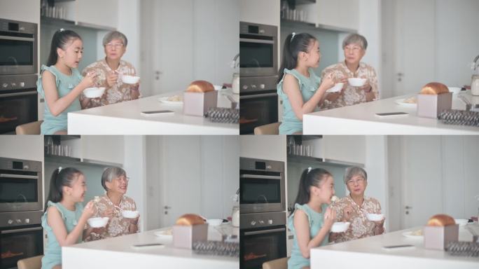 亚洲华裔老太太和孙女在厨房柜台吃中国饺子