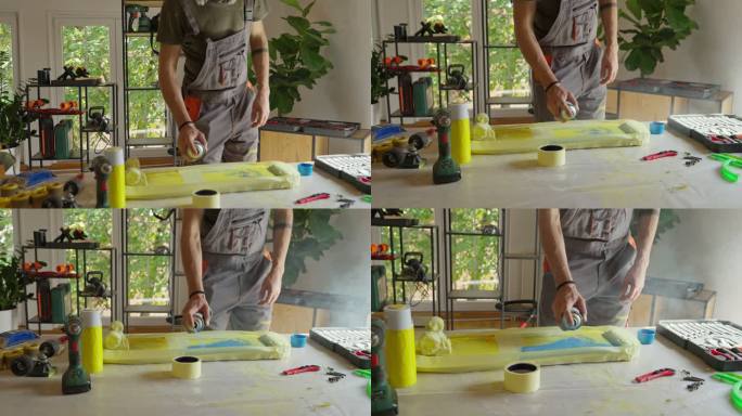 白人男性手工艺人，用喷漆在他的工作室里为滑板表面喷漆
