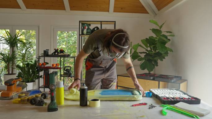 高加索男性手工艺人的肖像，在他的工作室用喷漆在滑板表面作画