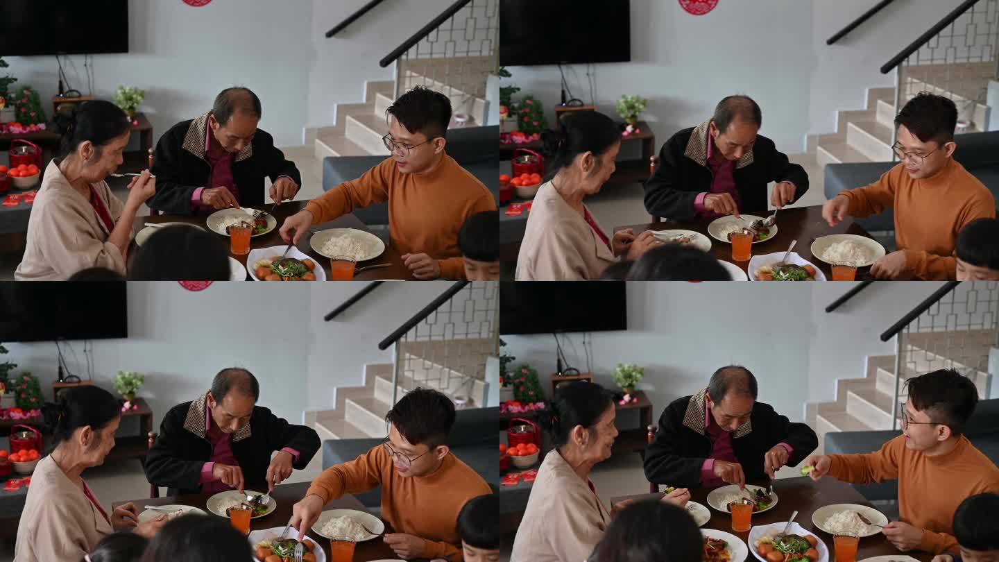 中国春节期间，一名亚洲男子在家里吃团圆饭时与母亲分享食物