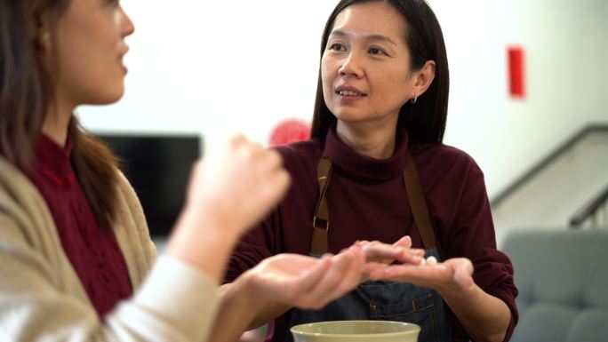 两名亚洲中国妇女在中国新年团圆饭上做汤圆