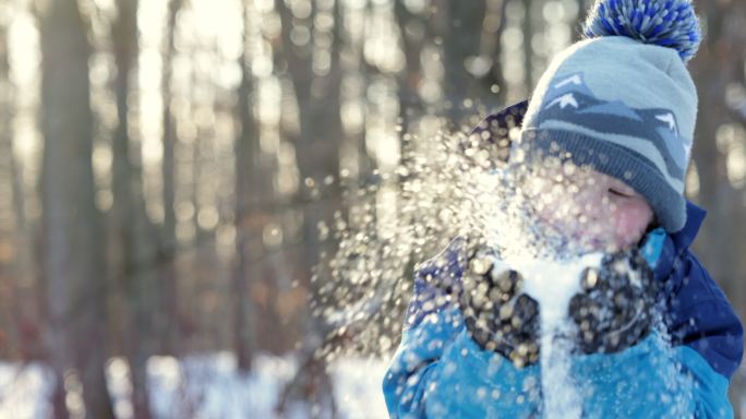 冬天森林里吹雪的小男孩