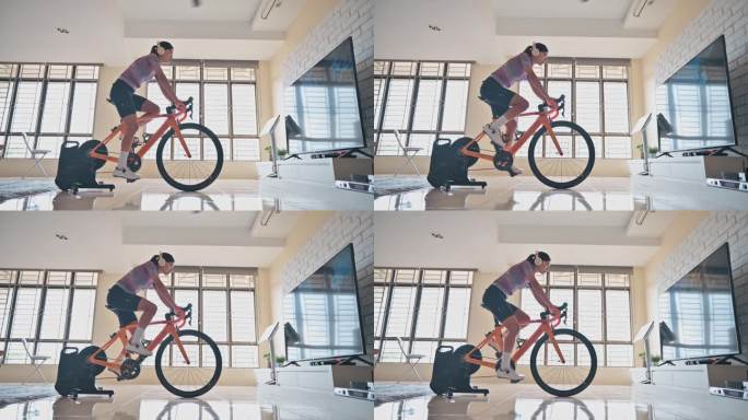 亚洲中国女子在家与固定自行车教练一起骑车
