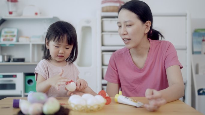 妈妈和他的女儿正在画鸡蛋