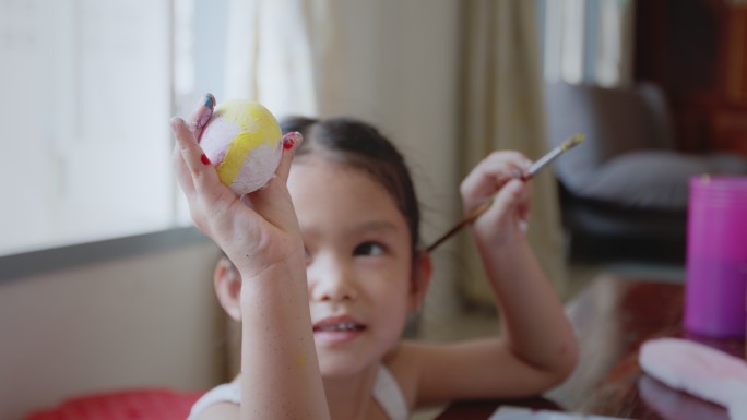 亚洲小女孩和家人在鸡蛋上涂色。孩子和家人准备复活节，画和装饰彩蛋。