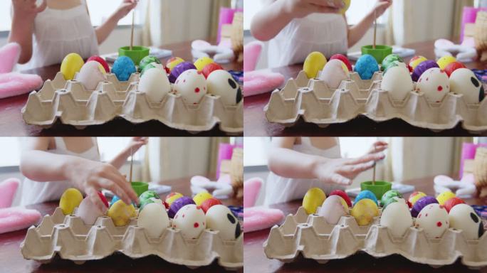 亚洲小女孩和家人在鸡蛋上涂色。孩子和家人准备复活节，画和装饰彩蛋。