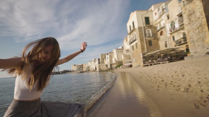 在塞法鲁老城的海滩上跳舞的少女