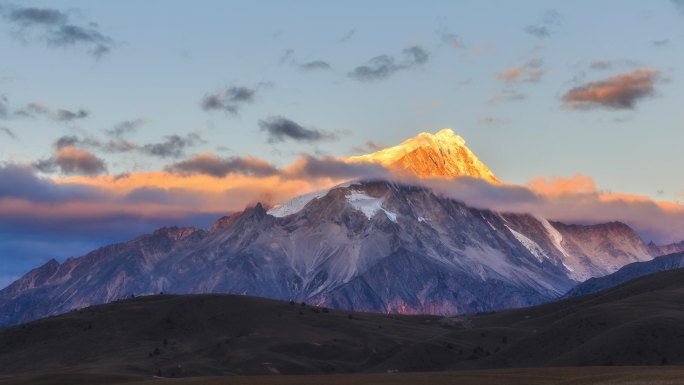 日出染红了白雪覆盖的山顶和云彩