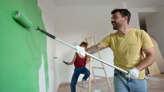 一对幸福的夫妇在粉刷他们的新公寓