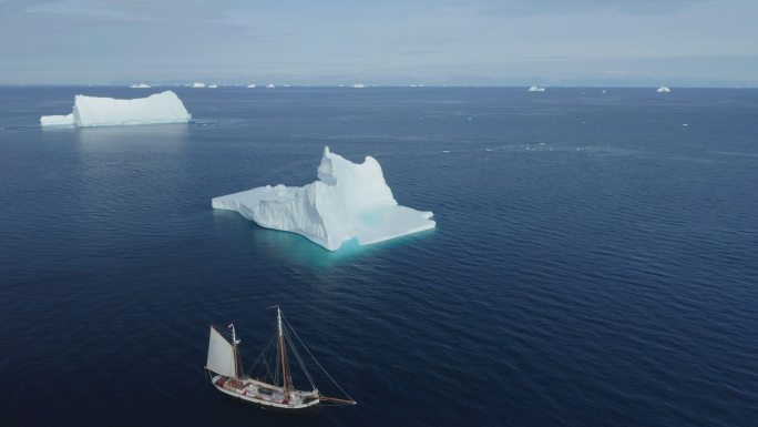 船只驶过格陵兰蓝海上的冰山