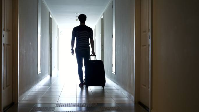 携带旅行行李的年轻人走向酒店房间