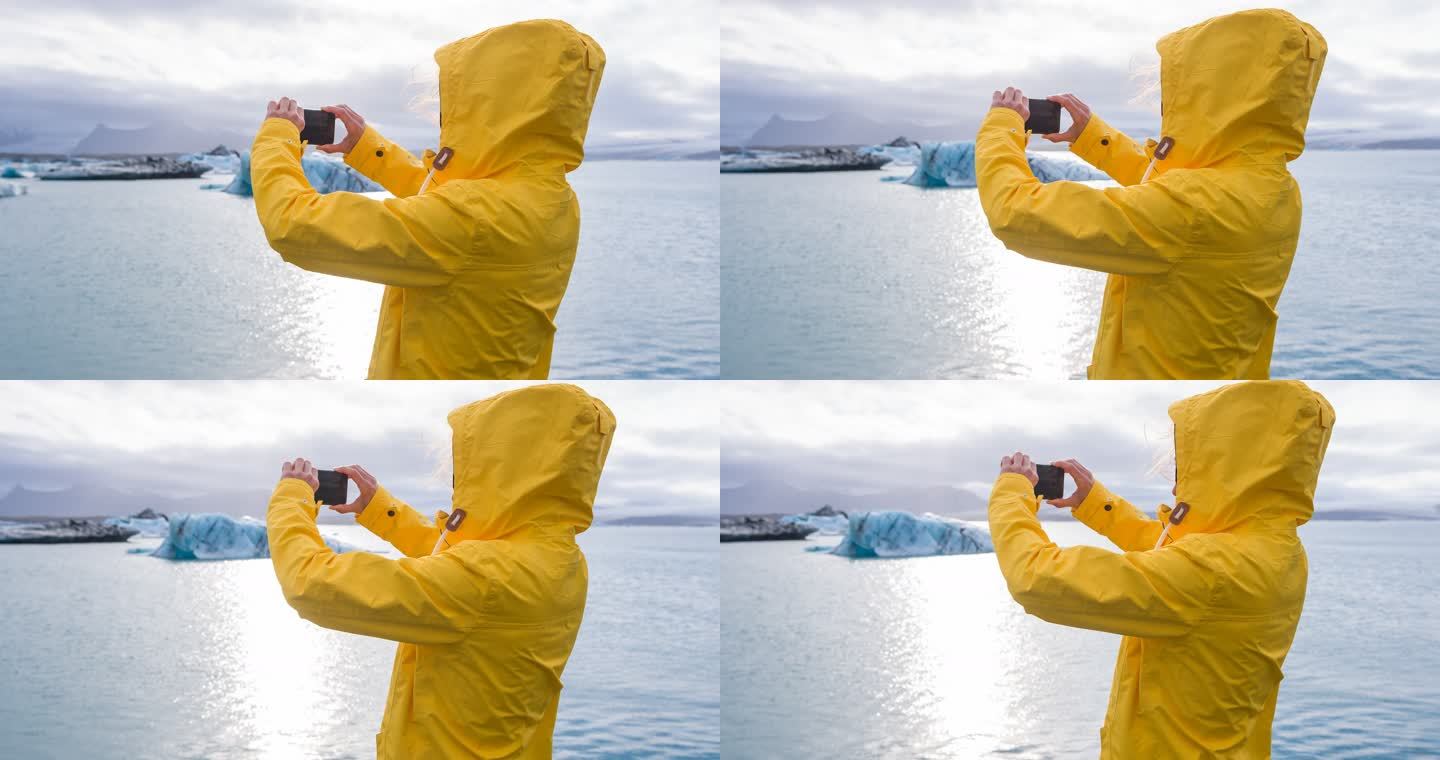 在冰岛的钻石海滩Breidamerkursandur上的女游客，用智能手机拍摄从Jokusarlon