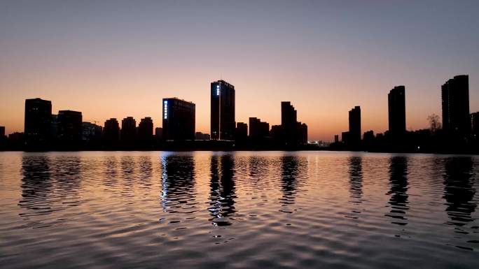 夕阳晚霞中的城市倒映在波光潋滟的湖水中