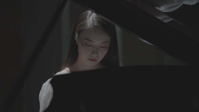 女生在黑暗环境下弹奏钢琴