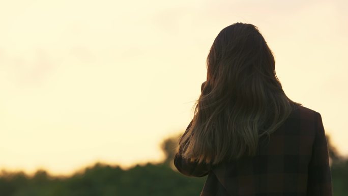 夕阳下美女撩头发背影