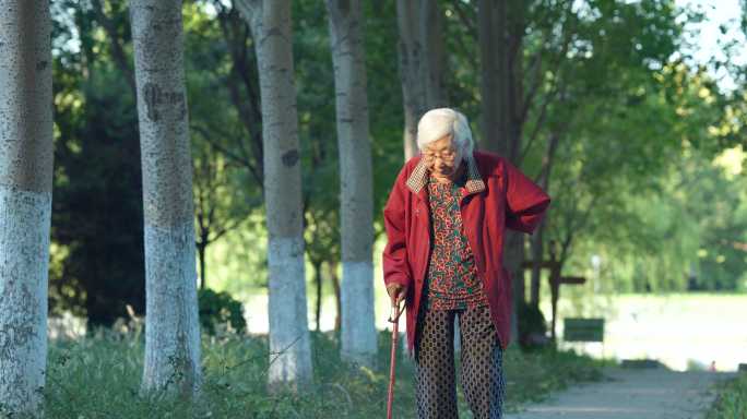 老人老年女性拄着拐杖在公园散步