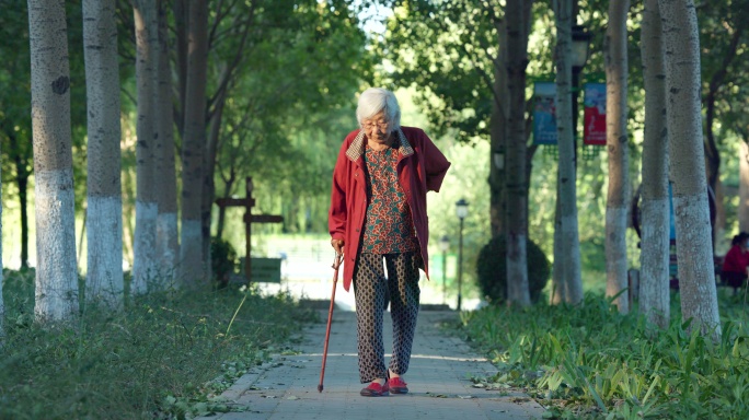 老人老年女性拄着拐杖在公园散步