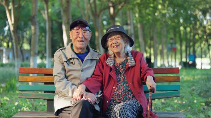 老人幸福的老年夫妇坐在公园长椅上聊天