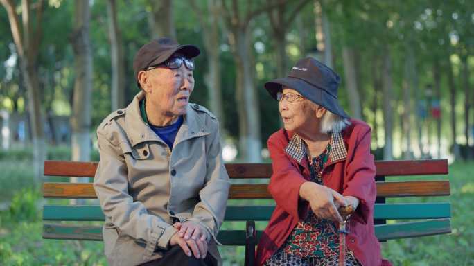 老人幸福的老年夫妇坐在公园长椅上聊天