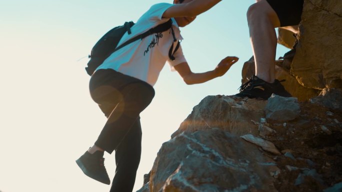 登山夕阳逆光剪影手拉手协助登顶 张开双臂