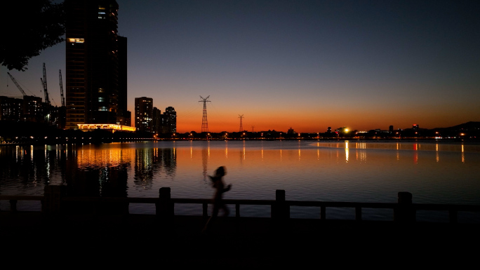 城市湖边晚霞夜跑的女生4K素材
