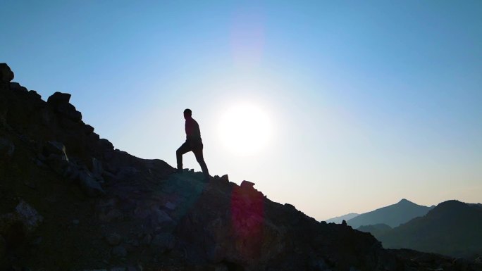 男人走向山顶登山剪影逆光人物眺望远方爬山