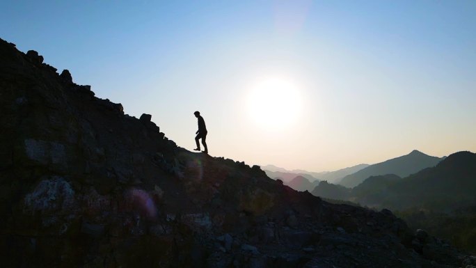 旅行者徒步走向山顶爬山攀登顶峰逆光人物