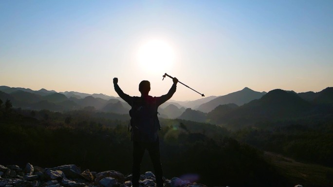 背着登山包走向山顶举手欢呼眺望远方登山者