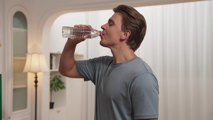男生在客厅喝瓶装水